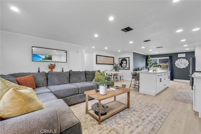 living room with light wood-type flooring, recessed lighting, crown molding, and baseboards