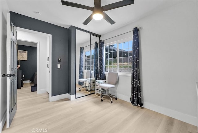 living area featuring light wood-style floors, baseboards, and ceiling fan