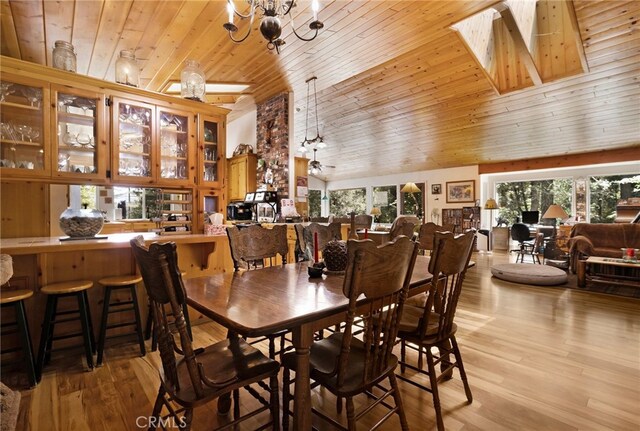 dining room featuring an inviting chandelier, wood ceiling, high vaulted ceiling, and light wood-style flooring