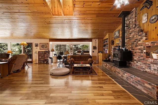 living area with a wood stove, wood ceiling, wood finished floors, and a healthy amount of sunlight
