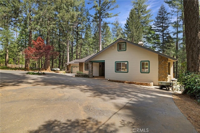 chalet / cabin with an attached garage, driveway, and a chimney