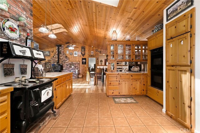 kitchen featuring a wood stove, light tile patterned floors, lofted ceiling, wood ceiling, and black appliances