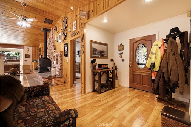 foyer with recessed lighting, wooden ceiling, a wood stove, and light wood-type flooring