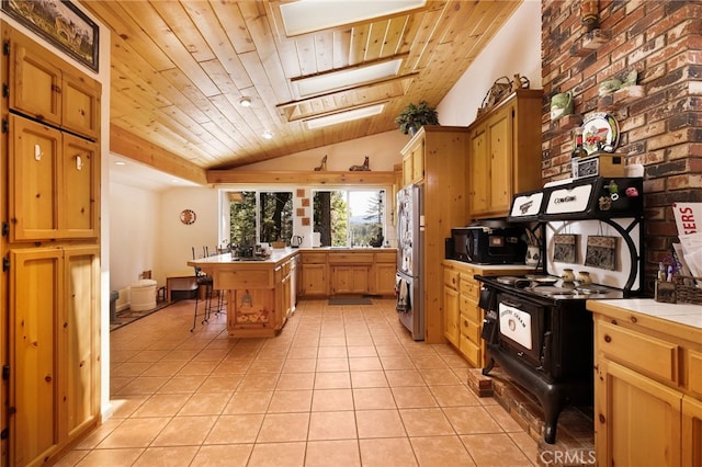 kitchen featuring a breakfast bar, tile counters, freestanding refrigerator, wood ceiling, and lofted ceiling with skylight