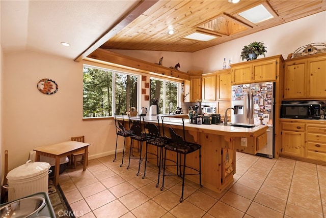 kitchen featuring a breakfast bar area, light tile patterned flooring, black microwave, and vaulted ceiling
