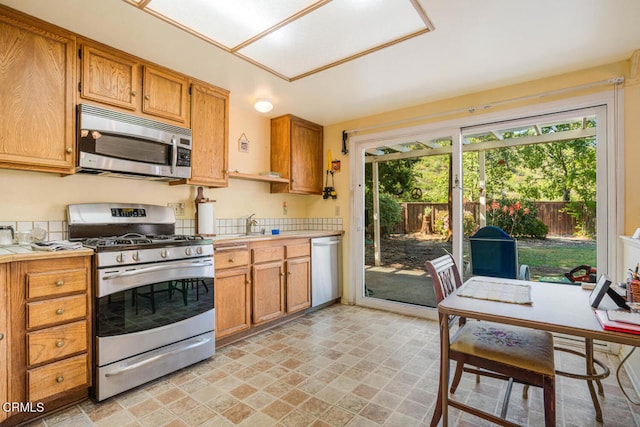 kitchen featuring brown cabinets, tile countertops, appliances with stainless steel finishes, and stone finish flooring