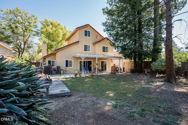 rear view of property featuring a pergola, stucco siding, a deck, a fenced backyard, and a chimney