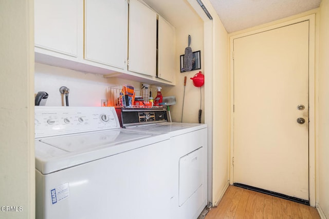 clothes washing area with separate washer and dryer, light wood-style flooring, and cabinet space