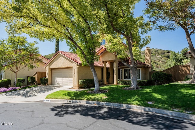 mediterranean / spanish home featuring a garage, fence, stucco siding, a tiled roof, and concrete driveway