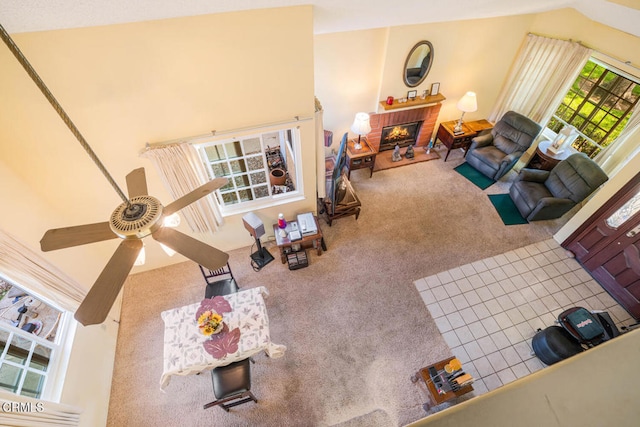 living area featuring ceiling fan, carpet, and a fireplace