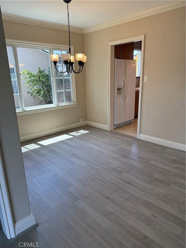 unfurnished dining area with baseboards, a notable chandelier, ornamental molding, and wood finished floors