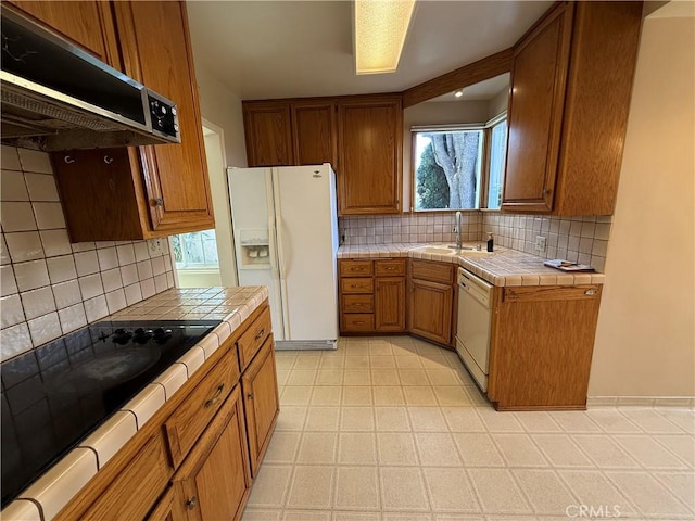 kitchen with white appliances, tile counters, plenty of natural light, ventilation hood, and a sink