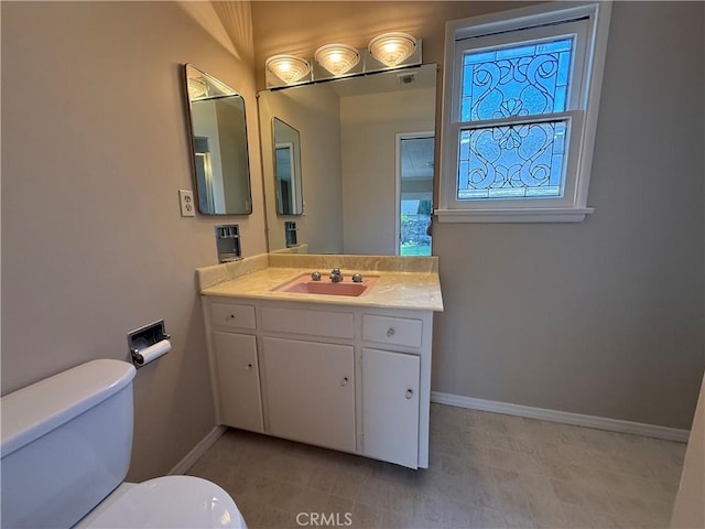 bathroom with baseboards, vanity, and toilet