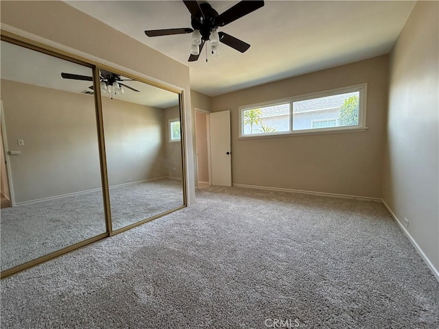 unfurnished bedroom featuring baseboards, ceiling fan, carpet, and a closet