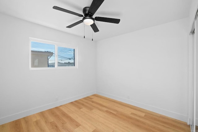 spare room featuring baseboards, light wood finished floors, and ceiling fan