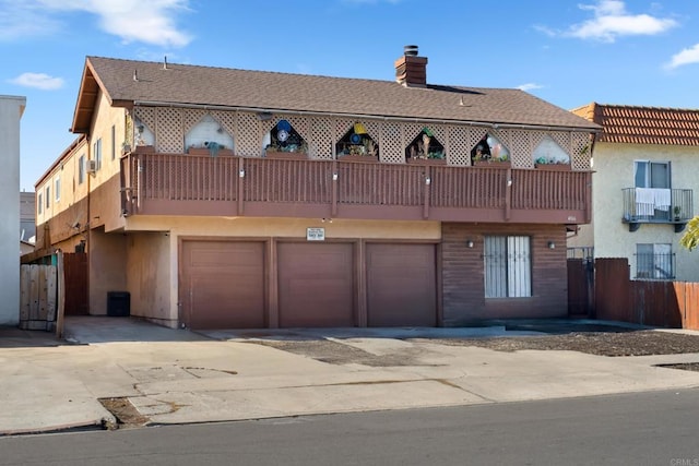 view of front of home featuring a garage, a chimney, and a balcony