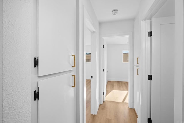 hall with baseboards and light wood finished floors
