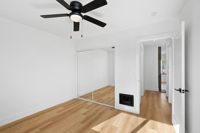 unfurnished bedroom with baseboards, ceiling fan, wood finished floors, and a closet