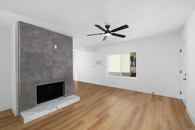 unfurnished living room with baseboards, a ceiling fan, light wood-style flooring, and a tile fireplace