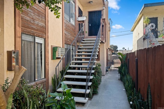 doorway to property featuring fence and stucco siding