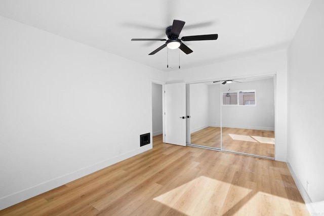 unfurnished bedroom with ceiling fan, visible vents, wood finished floors, baseboards, and a closet