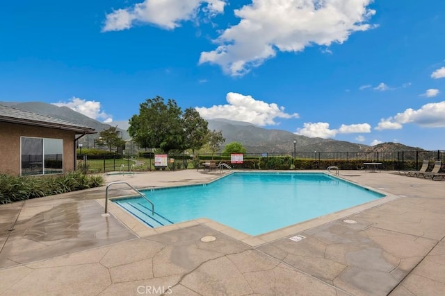 community pool featuring a patio, fence, and a mountain view