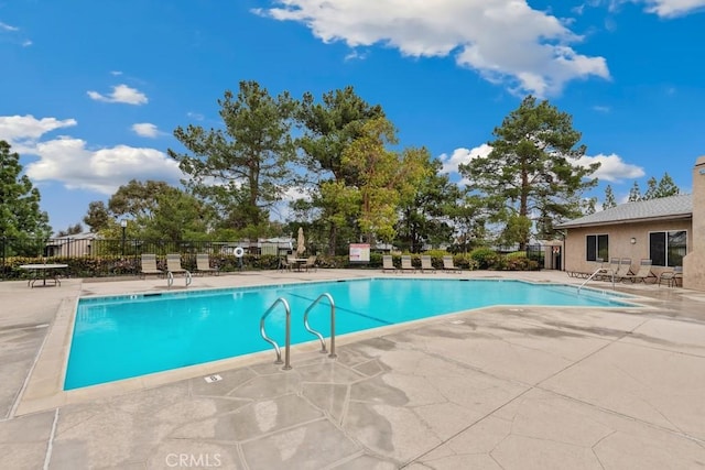 community pool with a patio area and fence