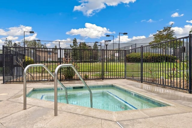 view of pool with a hot tub and fence