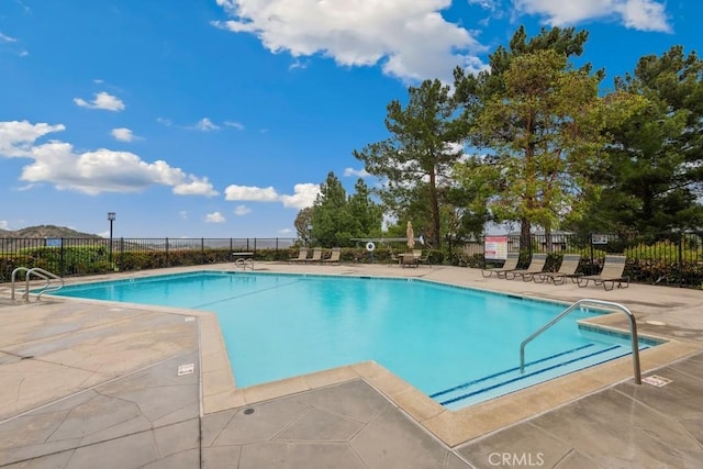 community pool with a patio and fence