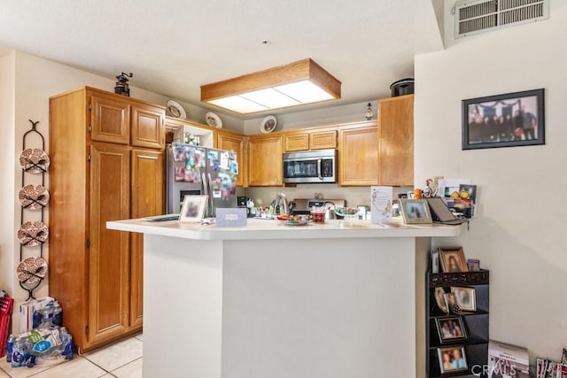 kitchen featuring visible vents, a peninsula, light countertops, light tile patterned floors, and stainless steel appliances