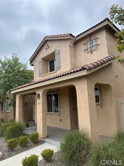 mediterranean / spanish home with a tiled roof, stucco siding, and covered porch