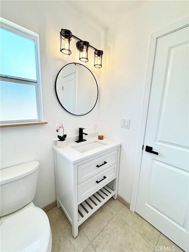 bathroom featuring toilet, tile patterned floors, baseboards, and vanity