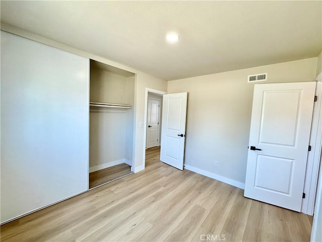 unfurnished bedroom featuring baseboards, visible vents, light wood finished floors, and a closet