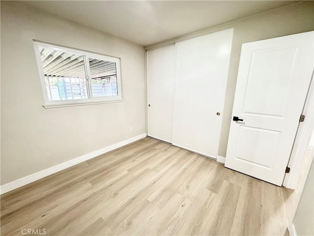 unfurnished bedroom featuring baseboards, wood finished floors, and a closet