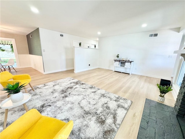 interior space featuring recessed lighting, visible vents, a fireplace with flush hearth, and wood finished floors