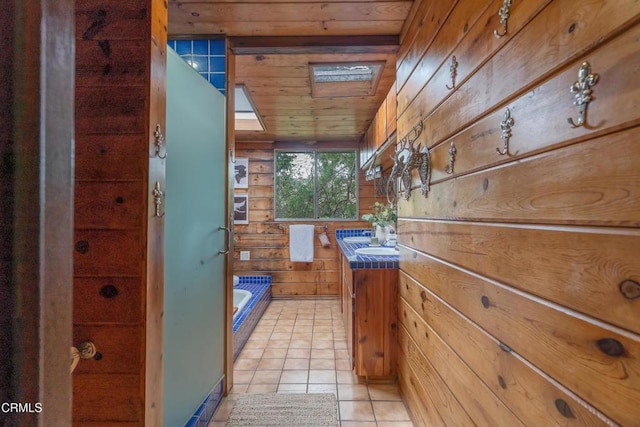 full bathroom featuring vanity, tile patterned floors, wood walls, wood ceiling, and tiled tub