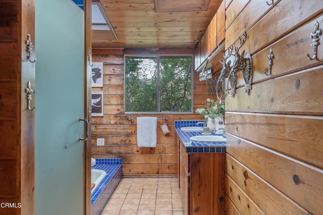 full bathroom with wooden walls, tile patterned floors, tiled tub, and vanity