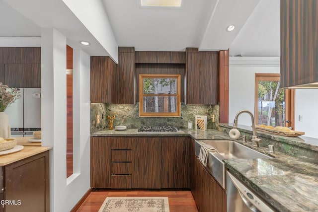 kitchen featuring decorative backsplash, dark stone countertops, stainless steel appliances, and light wood-type flooring