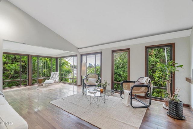 sunroom with wood-type flooring and high vaulted ceiling