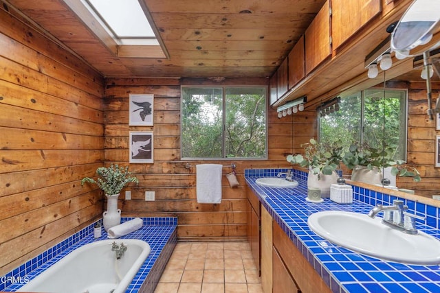 full bathroom with a sink, wood ceiling, tiled tub, and a skylight