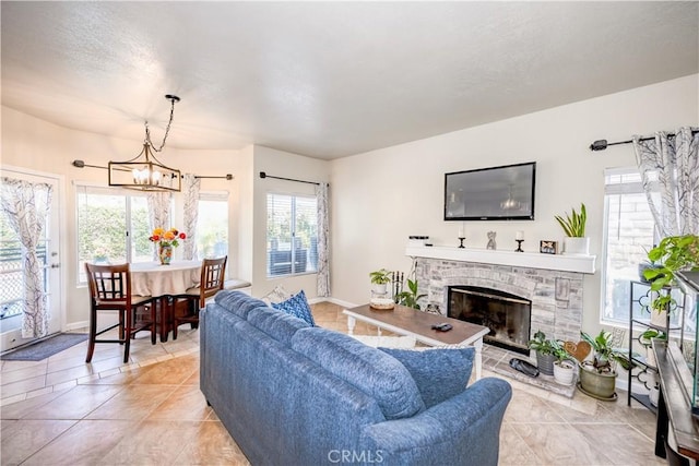 living area with plenty of natural light, light tile patterned floors, a chandelier, and a fireplace