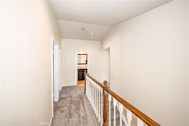 hallway with baseboards, an upstairs landing, and light carpet