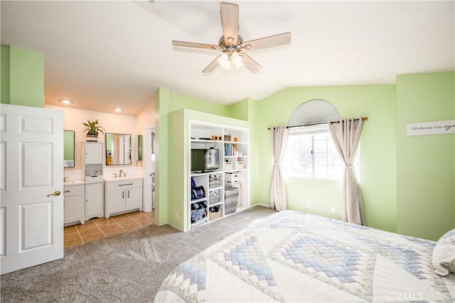 bedroom with lofted ceiling, light colored carpet, light tile patterned floors, a sink, and ensuite bath