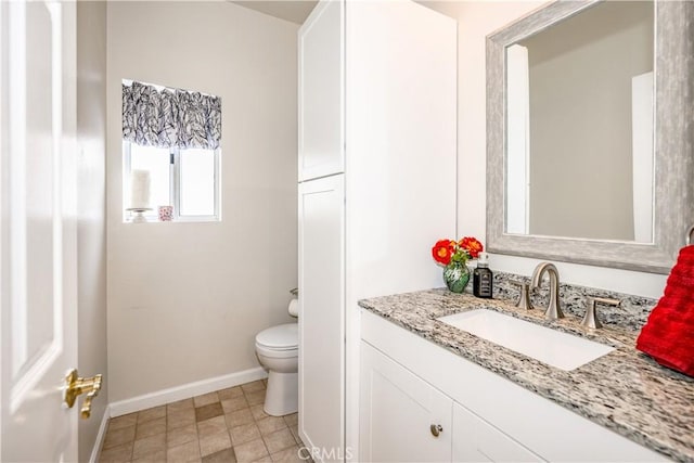 bathroom with baseboards, toilet, and vanity