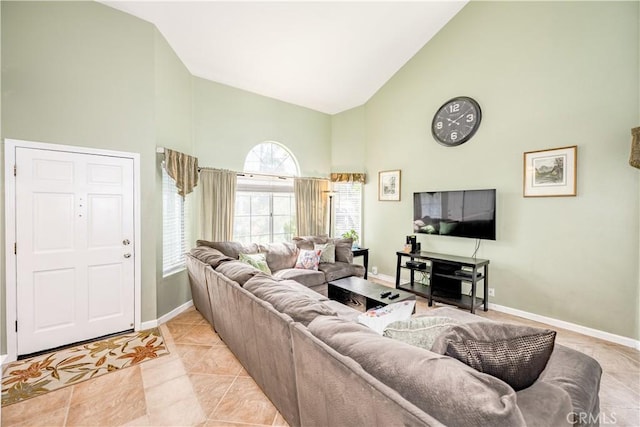 living room featuring high vaulted ceiling, baseboards, and light tile patterned flooring