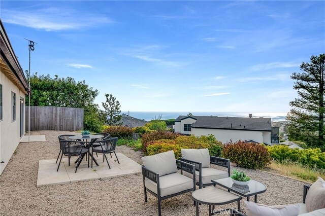 view of patio featuring fence, a water view, and outdoor lounge area