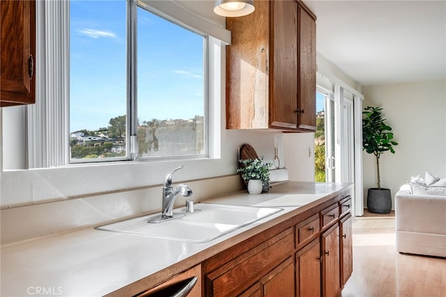 kitchen featuring plenty of natural light, a sink, brown cabinets, and light countertops