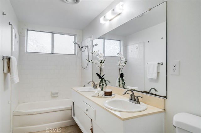 bathroom featuring double vanity, toilet, a sink, and bathtub / shower combination