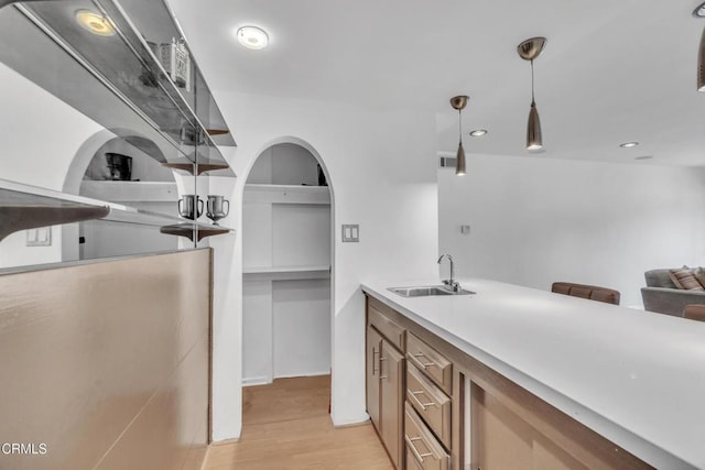 bar featuring recessed lighting, a sink, light wood-style flooring, and decorative light fixtures