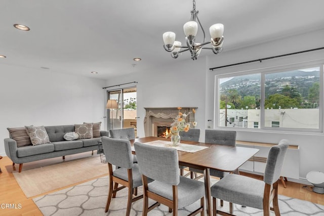 dining room with recessed lighting, light wood finished floors, a chandelier, and a lit fireplace
